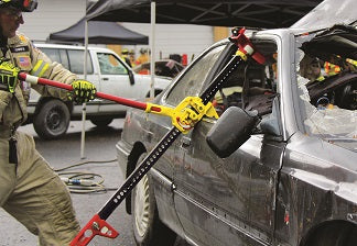 A fireman is using a first responder jack to widen the window of a car